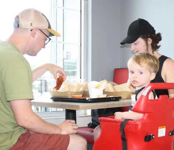 Family of mom, dad and child enjoy a chicken meal at the Rockin Chicken Shack restaurant in Wisconsin Dells.